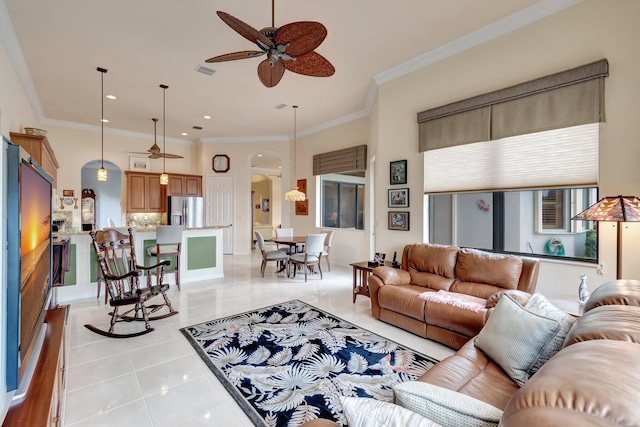 living area featuring visible vents, arched walkways, a ceiling fan, ornamental molding, and light tile patterned flooring