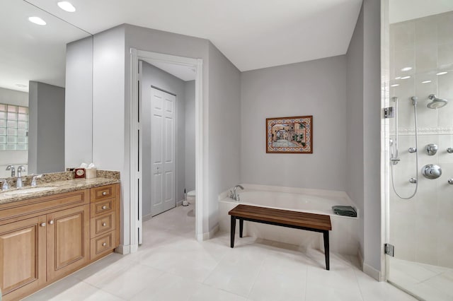 bathroom featuring toilet, a stall shower, a garden tub, and vanity