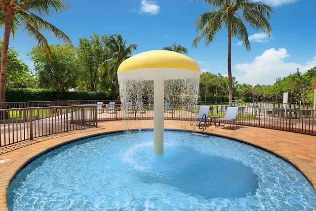 view of swimming pool featuring fence and a hot tub