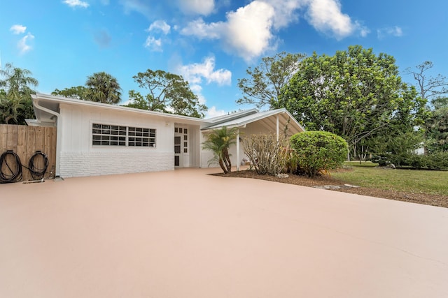 view of front of house with fence, concrete driveway, and brick siding