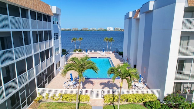 community pool with a water view, fence, and a patio