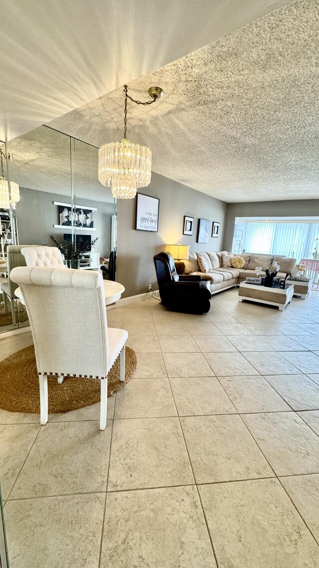 living room with a chandelier, a textured ceiling, baseboards, and tile patterned floors