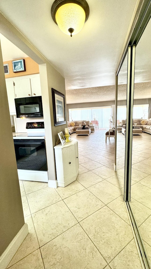 kitchen with light tile patterned floors, white cabinets, black dishwasher, light countertops, and freestanding refrigerator