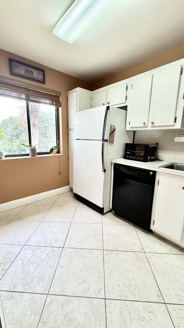 kitchen with black dishwasher, white cabinets, freestanding refrigerator, light countertops, and range with electric stovetop