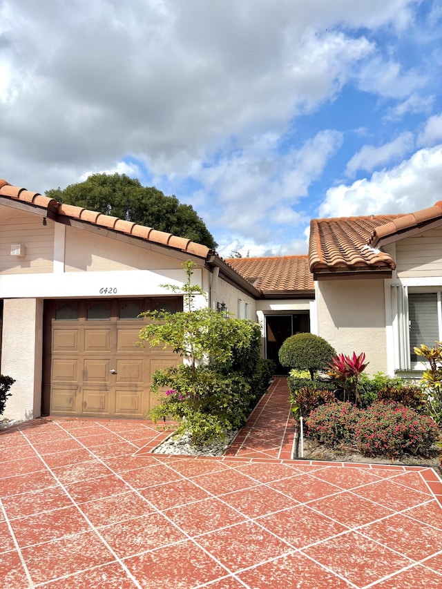 exterior space with a tiled roof, a garage, driveway, and stucco siding