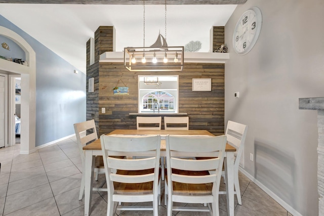 tiled dining room featuring wooden walls, baseboards, and a chandelier