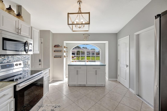 kitchen featuring appliances with stainless steel finishes, an inviting chandelier, light countertops, baseboards, and backsplash