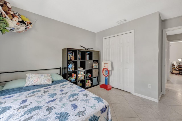 bedroom with baseboards, visible vents, light tile patterned floors, and a closet