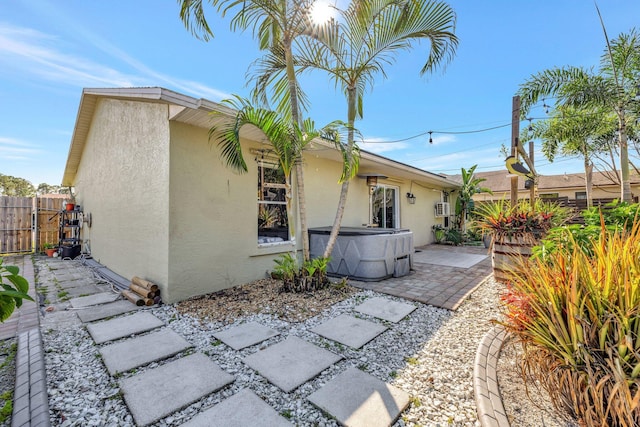 rear view of house with a patio, stucco siding, and a hot tub