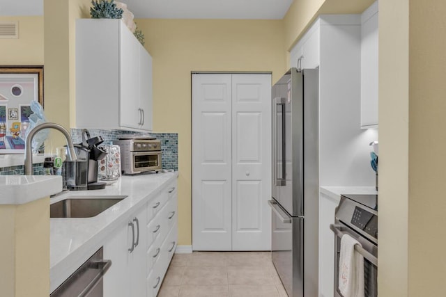 kitchen with stainless steel appliances, light tile patterned flooring, light countertops, and white cabinets