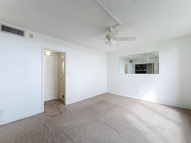 spare room featuring ceiling fan, a textured ceiling, visible vents, baseboards, and carpet