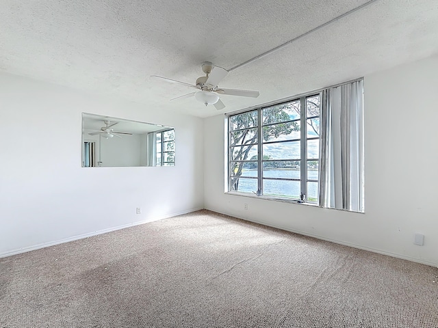 empty room featuring a textured ceiling, carpet floors, ceiling fan, and a wealth of natural light