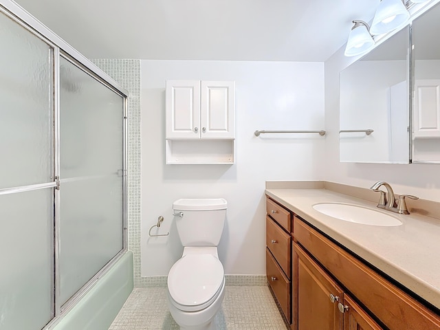 full bath featuring toilet, shower / bath combination with glass door, vanity, baseboards, and tile patterned floors