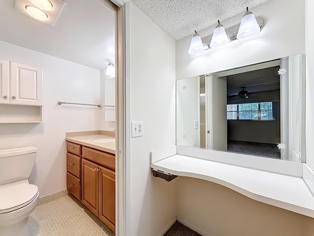 bathroom featuring baseboards, toilet, tile patterned floors, a textured ceiling, and vanity