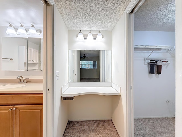 bathroom with ceiling fan, a spacious closet, a textured ceiling, and vanity