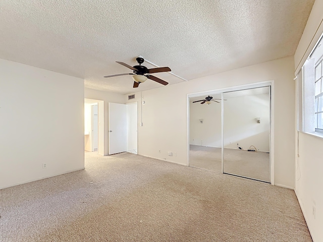 unfurnished bedroom with a closet, visible vents, a textured ceiling, and light colored carpet