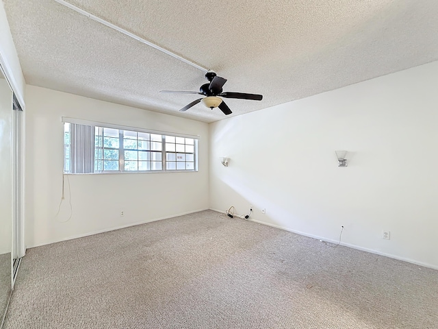 empty room featuring ceiling fan, a textured ceiling, baseboards, and carpet flooring