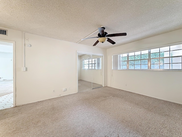 unfurnished room with ceiling fan, visible vents, a textured ceiling, and light colored carpet