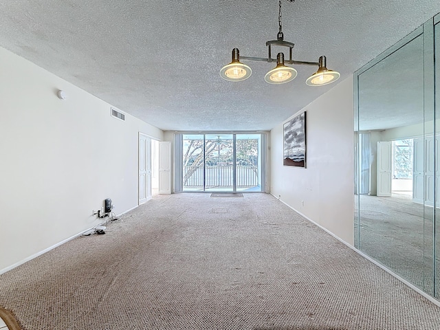 unfurnished living room featuring carpet, visible vents, and a textured ceiling