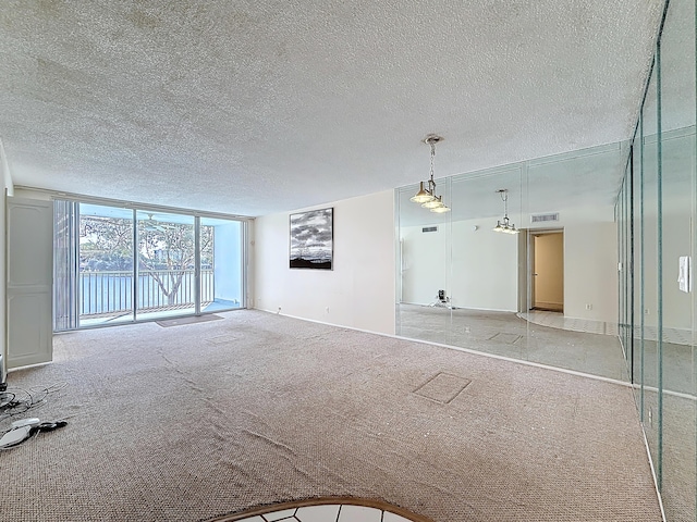 unfurnished room featuring light carpet, visible vents, a wall of windows, and a textured ceiling