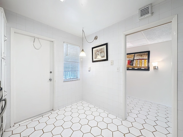 foyer with ornamental molding and visible vents