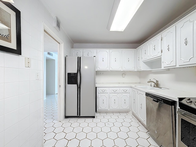 kitchen with a sink, tile walls, white cabinets, light countertops, and appliances with stainless steel finishes