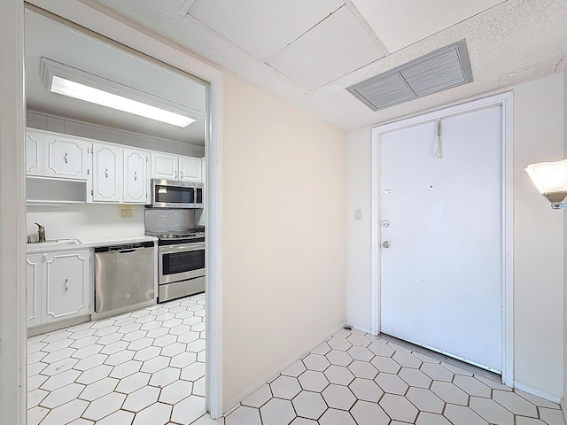 kitchen with light floors, stainless steel appliances, light countertops, visible vents, and white cabinetry