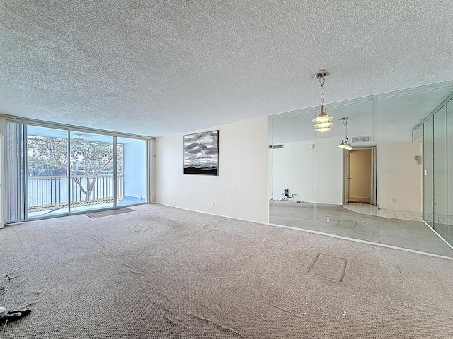 unfurnished living room with carpet floors, floor to ceiling windows, visible vents, and a textured ceiling