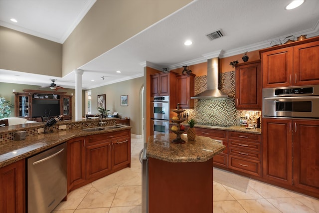 kitchen featuring stainless steel appliances, a sink, visible vents, wall chimney range hood, and decorative columns