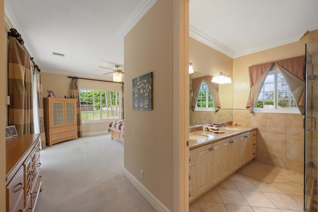 ensuite bathroom with plenty of natural light, a sink, and crown molding