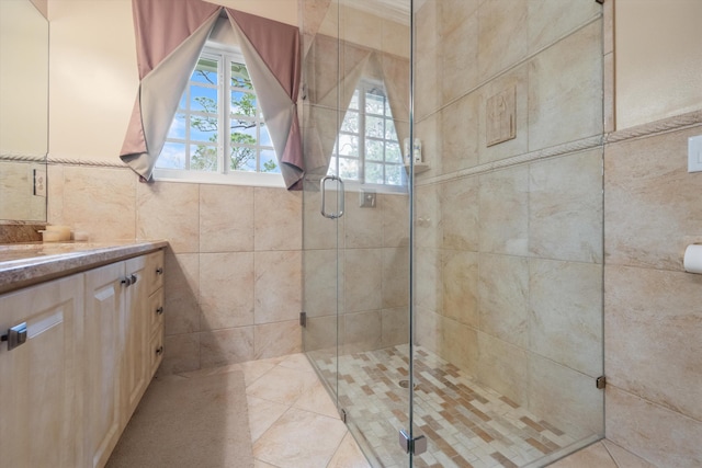 bathroom featuring vanity, a shower stall, and tile walls