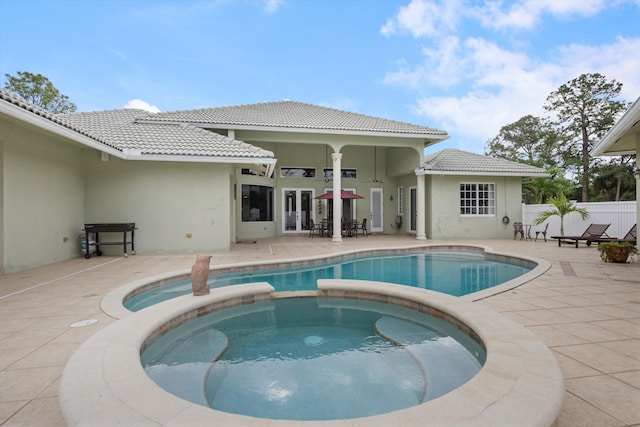 view of pool with a patio area, fence, and a pool with connected hot tub