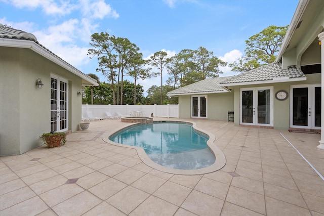 view of pool featuring french doors, a patio area, a fenced backyard, and a pool with connected hot tub