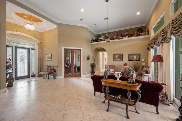 interior space featuring arched walkways, light tile patterned flooring, a towering ceiling, baseboards, and crown molding