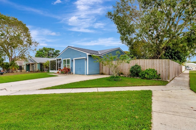 view of front of house with metal roof, an attached garage, fence, driveway, and a front yard