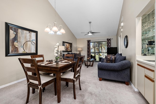 dining space with light carpet, an inviting chandelier, baseboards, and high vaulted ceiling