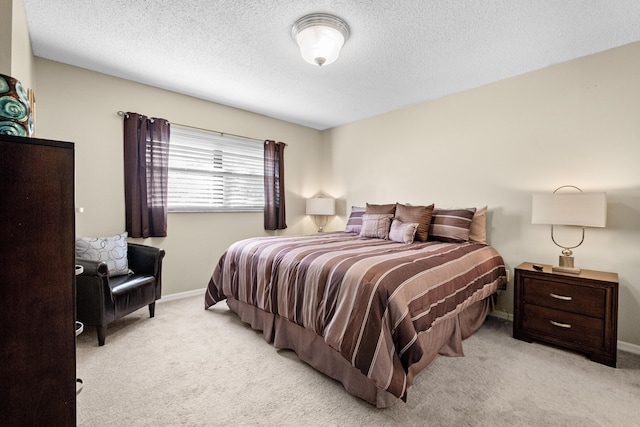 bedroom featuring light carpet, baseboards, and a textured ceiling