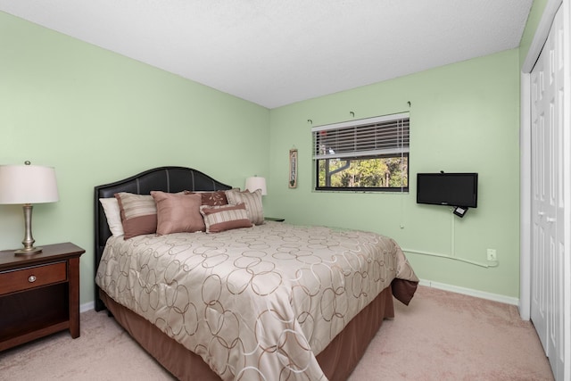 bedroom featuring baseboards, a closet, and light colored carpet