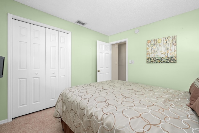 bedroom featuring a textured ceiling, a closet, visible vents, and light colored carpet