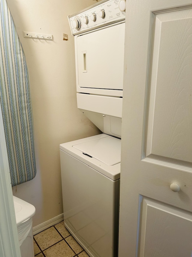 washroom with laundry area, light tile patterned floors, baseboards, and stacked washer and clothes dryer