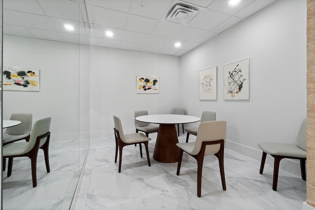 dining area featuring marble finish floor, baseboards, visible vents, and a drop ceiling