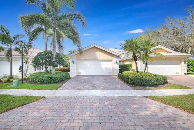 view of front of house with a garage, decorative driveway, and stucco siding