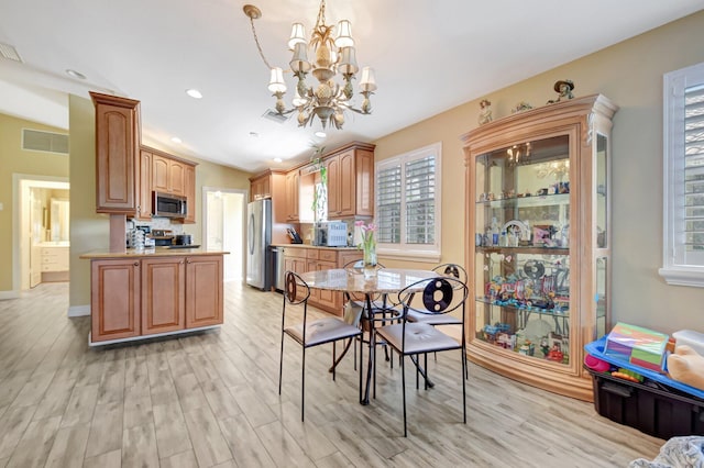 kitchen with stainless steel appliances, visible vents, hanging light fixtures, light countertops, and light wood finished floors