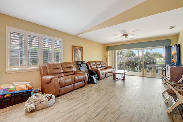 living room with lofted ceiling, a ceiling fan, visible vents, and light wood-style floors