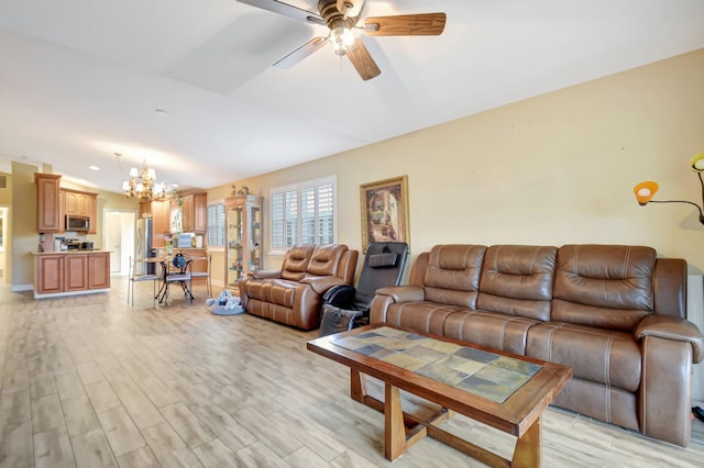 living area featuring light wood-type flooring, vaulted ceiling, and ceiling fan with notable chandelier