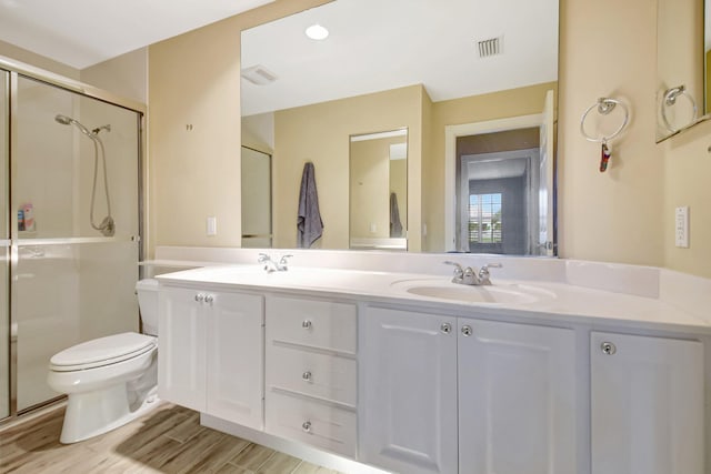 full bathroom with double vanity, visible vents, toilet, wood finished floors, and a sink