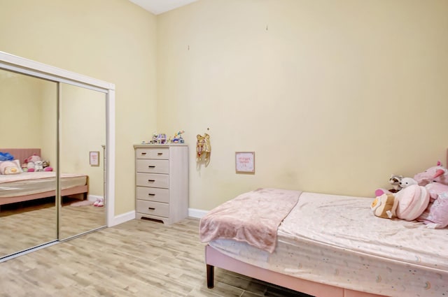 bedroom with baseboards, a closet, and light wood-style floors