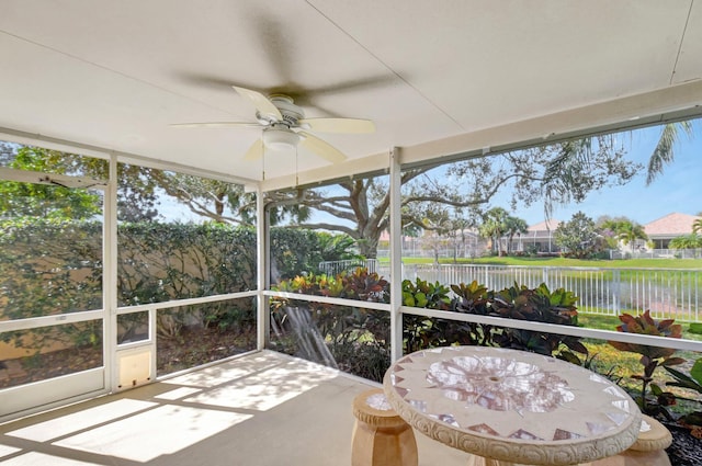 sunroom with a water view and ceiling fan