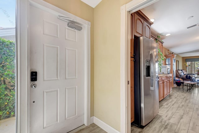 interior space with visible vents, baseboards, light countertops, stainless steel refrigerator with ice dispenser, and light wood finished floors