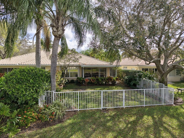 view of front of property with a front yard, stucco siding, a tile roof, and fence private yard